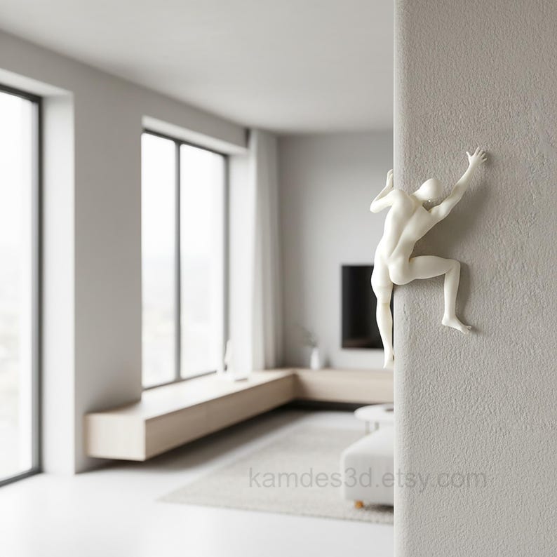 May include: A white wall-mounted sculpture depicting a human figure in a climbing pose, with arms and legs extended as if scaling the vertical edge of a textured wall. The figure is smooth, matte, and minimalist in its anatomical representation.
