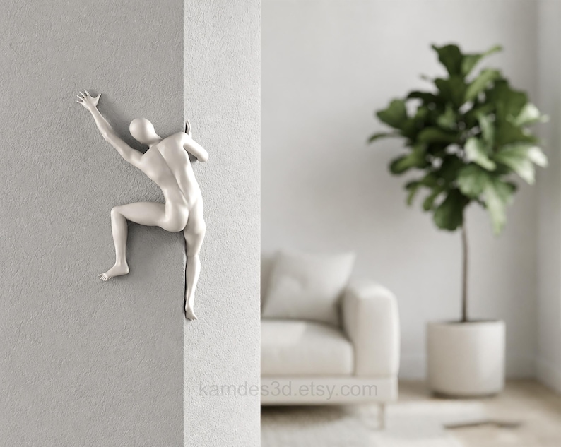 May include: A matte white wall sculpture depicting a stylized human figure climbing around the corner of a wall. The figure is shown in a dynamic pose with one arm extended upward and legs bent as if gripping the edge of the wall surface.