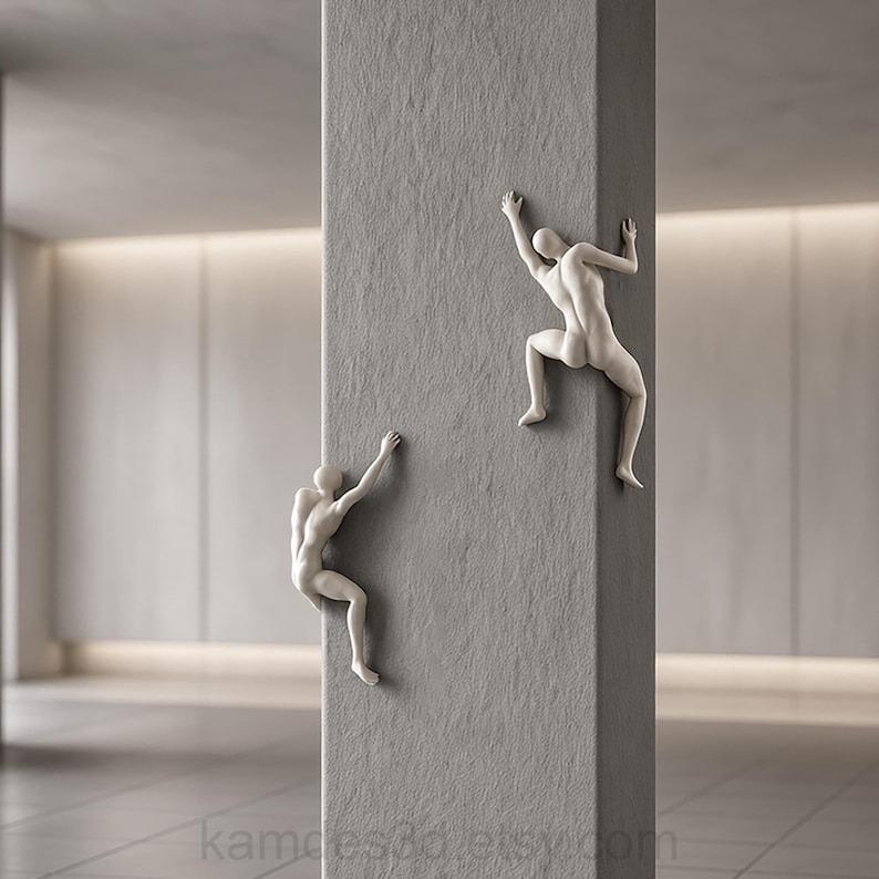 May include: Two off-white, abstract human-shaped sculptures are mounted on a textured gray vertical pillar. The figures are depicted in climbing poses, with one positioned higher than the other, both featuring smooth, featureless surfaces.