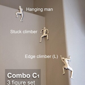 May include: A set of three white wall-mounted figurines depicting climbing figures. The set includes a hanging man, a stuck climber, and an edge climber (L). The text on the image labels these as Combo C1 3 figure set as shown.