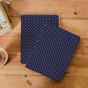 Könnte beinhalten: Ein marineblaues Notizbuch mit weißem Polka-Dot-Muster. Das Notizbuch ist geöffnet und zeigt die Innenseiten. Der Hintergrund ist eine Holzoberfläche mit einem Wählscheibentelefon und einer Kaffeetasse.