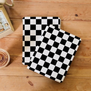 May include: Two black and white chequered notebook covers. The covers are made of a durable material and have a sleek, modern design.