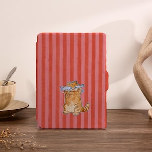 May include: A red and pink striped tablet case featuring a cartoon cat holding fish. The cat is orange with blue and white fish. The case is on a wooden surface.