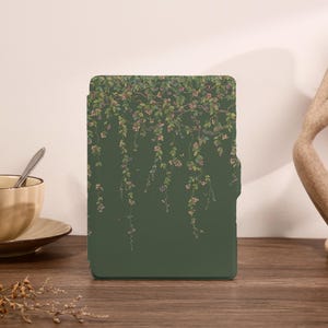 May include: A green tablet case with a floral design of hanging vines and pink and green leaves. The case is rectangular with a solid green background. The floral pattern is at the top and cascades down the front of the case.