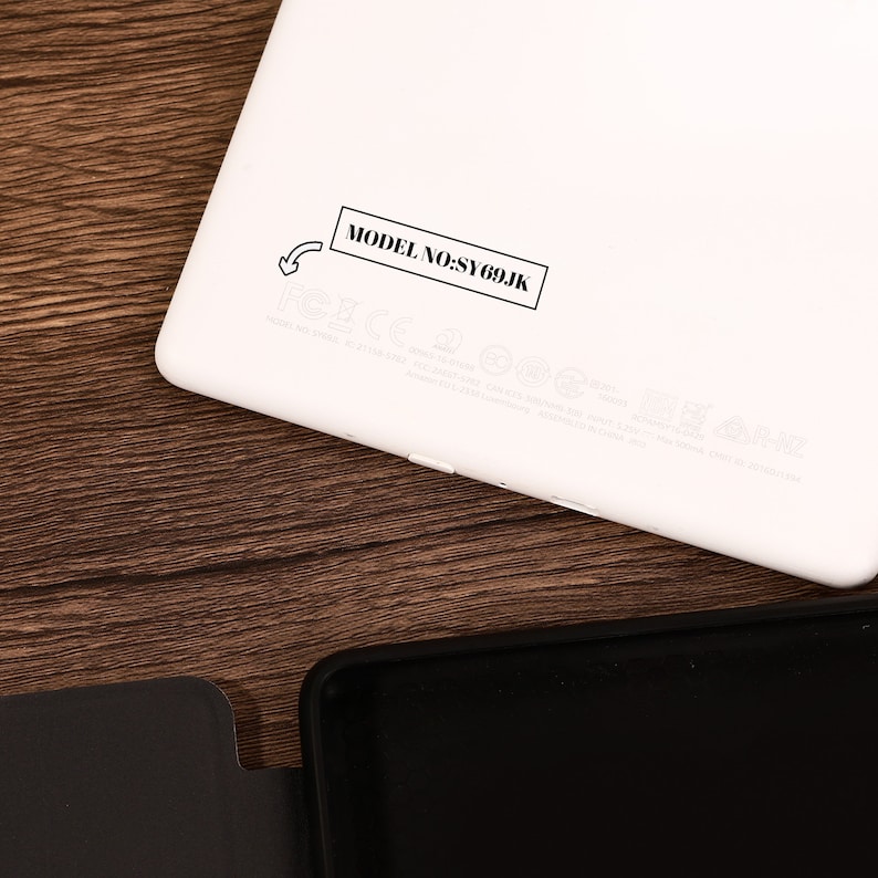 May include: A white electronic tablet device with rounded corners, featuring a black rectangular label printed with the text MODEL NO:SY69JK and a small arrow icon pointing toward the text, alongside various faint regulatory markings and symbols.
