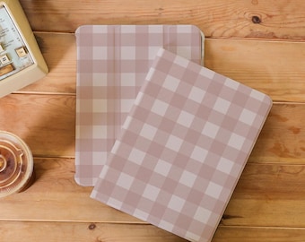 Op de afbeelding: Twee lichtroze en wit geruite tablethoezen worden weergegeven op een houten oppervlak. De hoezen zijn rechthoekig met afgeronde hoeken. Het patroon is een klassiek ruitjesontwerp. De hoezen zijn waarschijnlijk ontworpen om een tablet te beschermen.