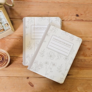 May include: Two composition notebooks with a floral design. The notebooks are white with grey floral illustrations and the words "Composition" and "Composition Book" printed on the front.