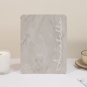 May include: A gray marble-patterned tablet case with the name "Annabelle" written in white script on the side.