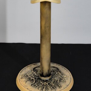May include: A cream-colored hat stand with a fluted column and a round base with a decorative design.