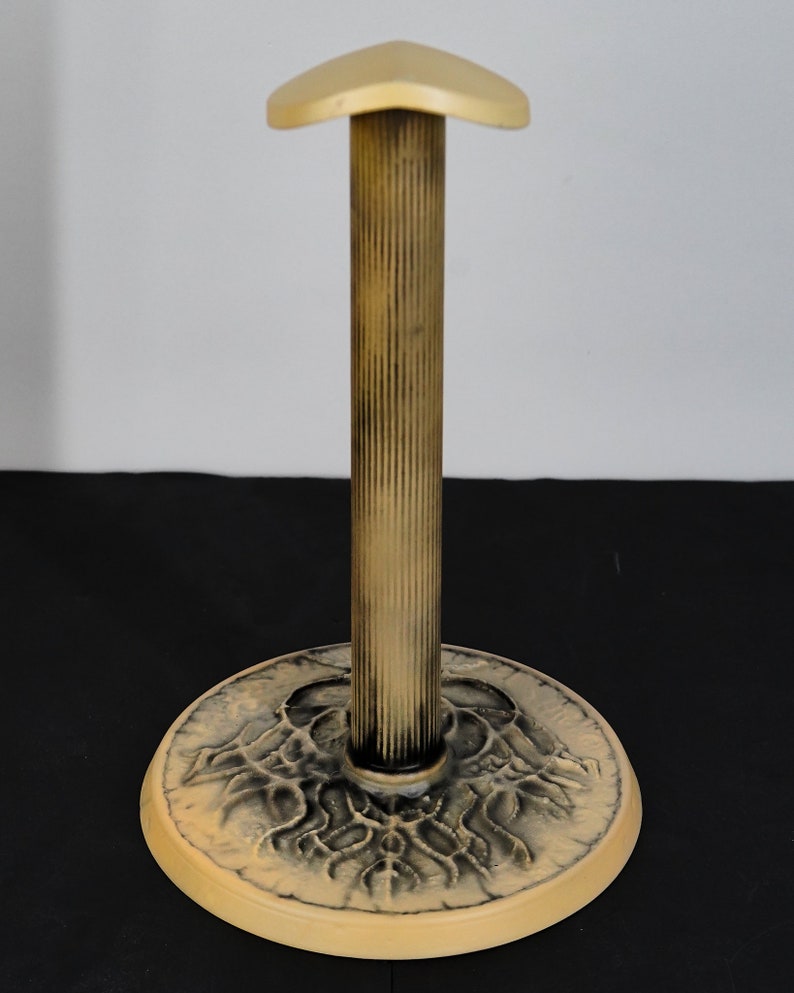 May include: A cream-colored hat stand with a fluted column and a round base with a decorative design.