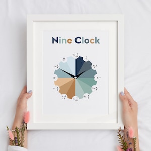 May include: A white framed print with the title "Nine Clock" and a clock face divided into 12 sections with different shades of blue, green, and brown. Each section has a fraction with 9 as the denominator.