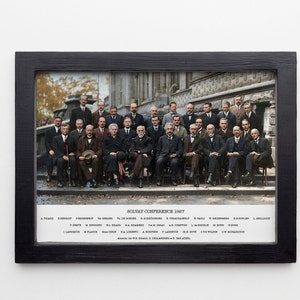 May include: A black and white photo of a group of men in suits standing in front of a building. The photo is titled "Solvay Conference 1927" and lists the names of the men in the photo.