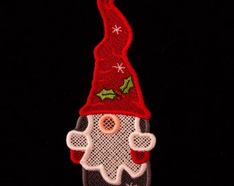 May include: Red and white felt gnome ornament with a green holly sprig and red berries. The gnome has a white beard and a black hat.
