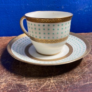 May include: A white ceramic mug with a black handle and the text "But First, Coffee" in a handwritten style. The mug is on a white surface. The mug is 10 cm tall.