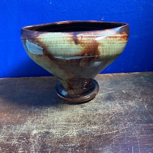 May include: A handmade ceramic bowl with a wide, open top and a flared base. The bowl features a blend of brown and green hues, with darker brown streaks and a glossy finish. The bowl is approximately 15 cm in diameter and 10 cm tall.