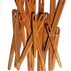 May include: A group of 14 wooden knitting needles with a natural brown finish. The needles are arranged in a random pattern, with some overlapping.