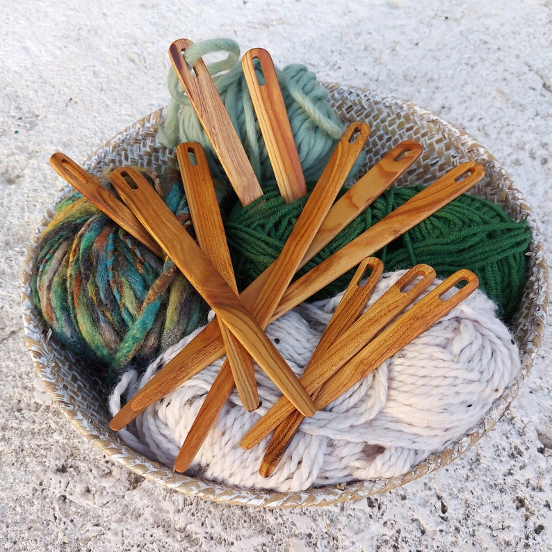 May include: A basket filled with colourful yarn and wooden knitting needles. The needles are arranged in a fan shape and are made of natural wood.