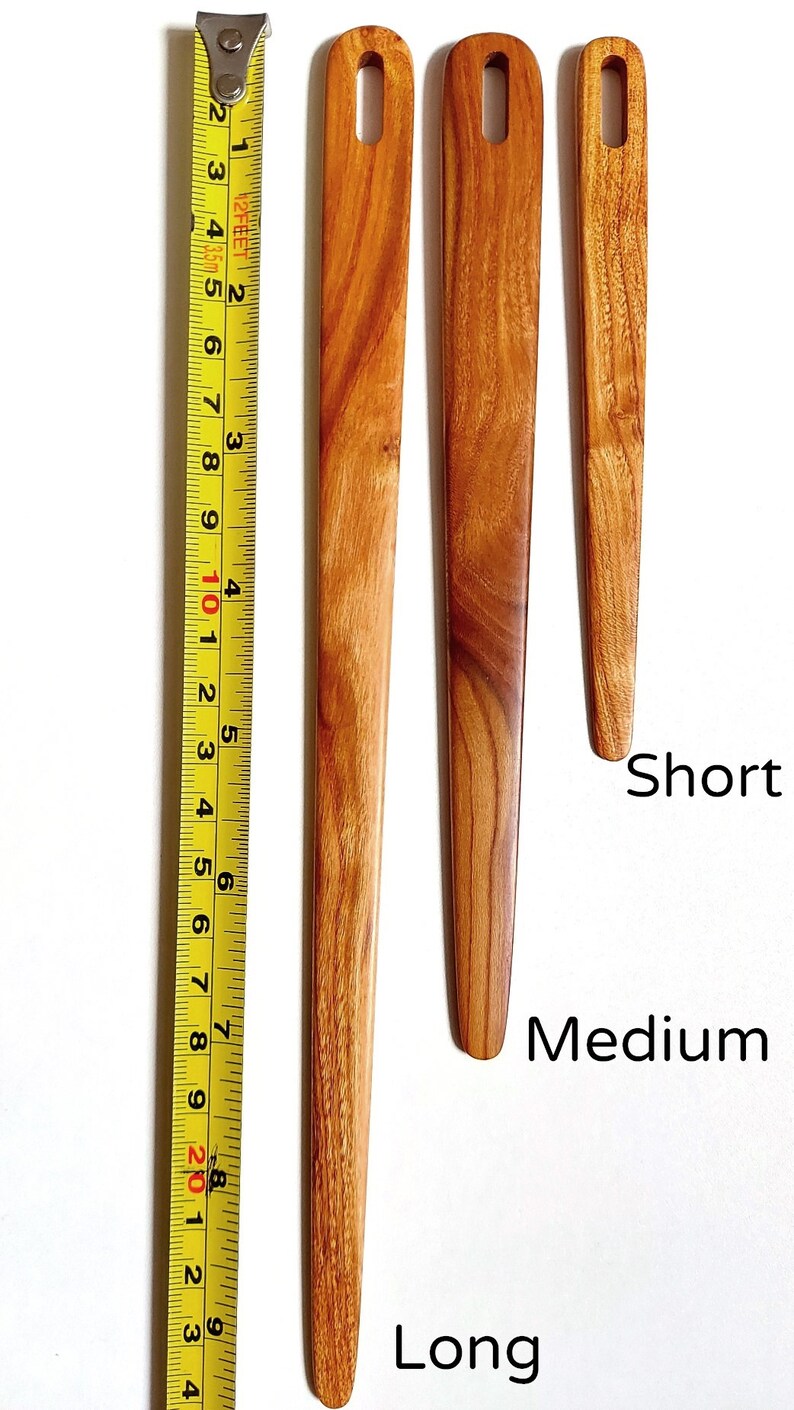 May include: Three wooden knitting needles of different lengths: short, medium, and long. The needles are made of light brown wood with a natural grain pattern. The needles have a loop at the top for holding yarn.