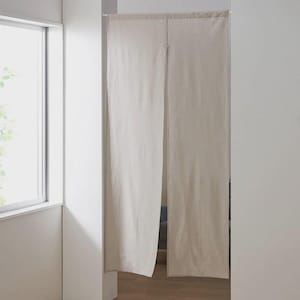 Op de afbeelding: Twee roomdividers van off-white stof, hangend aan een stang. De dividers zijn gemaakt van een lichtgewicht, geweven stof en hangen aan een eenvoudige stang. De stof is licht gekreukt, wat het een casual en ontspannen uitstraling geeft.