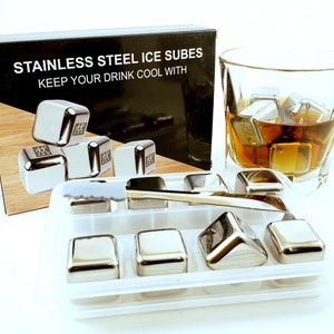 May include: Stainless steel ice cubes in a clear plastic tray with a silver tong. The ice cubes are in a glass of amber liquid. The box says "Stainless Steel Ice Cubes Keep Your Drink Cool With".