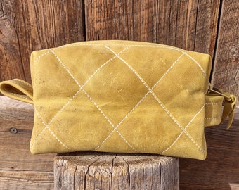 May include: A yellow quilted leather makeup bag with white stitching.