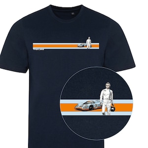 Puede incluir: Camiseta azul marino con un gráfico de un coche de carreras vintage, un piloto y el texto "Track Limits". El diseño incluye rayas naranjas y celeste. La camiseta tiene cuello redondo.