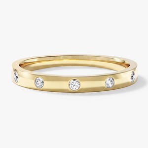May include: A yellow gold band ring featuring five evenly spaced, flush-set round brilliant cut diamonds. The metal has a polished, reflective finish, and the stones are set directly into the smooth, flat surface of the circular band.