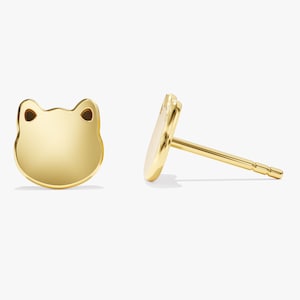 Op de afbeelding: Een paar gouden oorbellen met een kikker-vorm. De oorbellen zijn klein en delicaat, en ze zouden een geweldig cadeau zijn voor iemand die van kikkers houdt.