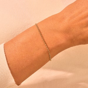 May include: A delicate gold chain bracelet on a person's wrist.