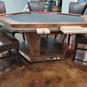 May include: Octagonal wooden game table with a dark gray felt top and a built-in storage drawer. The table has a light wood finish and features LED lights around the perimeter of the table top.