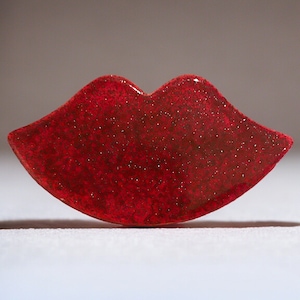 May include: A red glitter lip-shaped ceramic ornament.