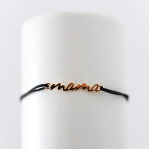 May include: A black string bracelet with a gold charm that says "mama".