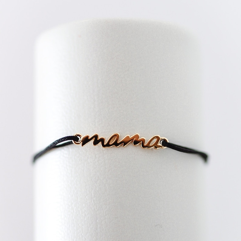 May include: A black string bracelet with a gold charm that says "mama".