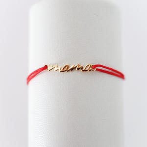 May include: A red string bracelet with a gold charm that says "mama".