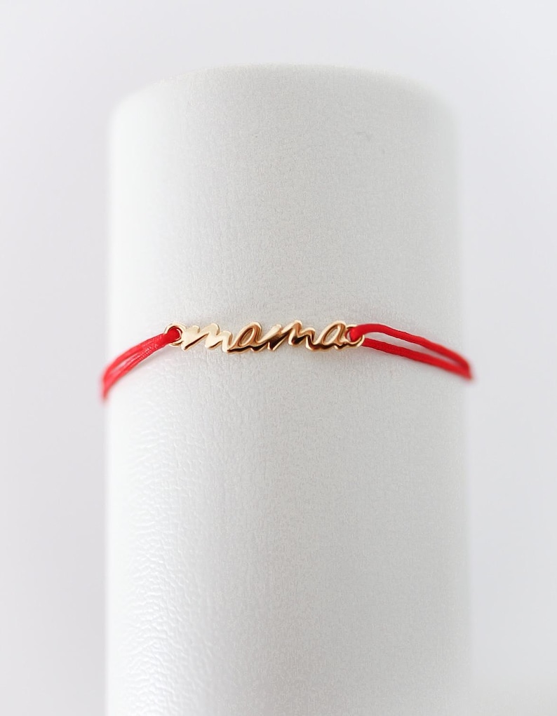 May include: A red string bracelet with a gold charm that says "mama".