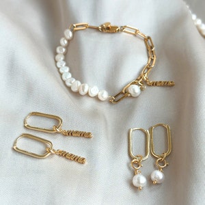 Pu&ograve; includere: Un set di gioielli in oro con un braccialetto di perle con una catena d'oro, un paio di orecchini a cerchio d'oro con un ciondolo di perla e un paio di orecchini d'oro con un ciondolo di perla e un ciondolo "mamma".