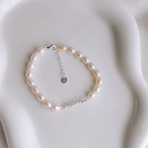 May include: A delicate pearl bracelet with a silver charm that reads "mama".