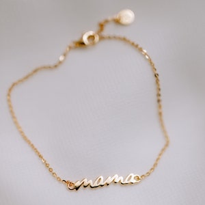 May include: A gold chain bracelet with the word "mama" in cursive script.
