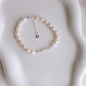 May include: A delicate pearl bracelet with a silver charm that reads "mama".