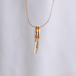 May include: Gold hoop earrings with a dangling charm that says "mama" in cursive.