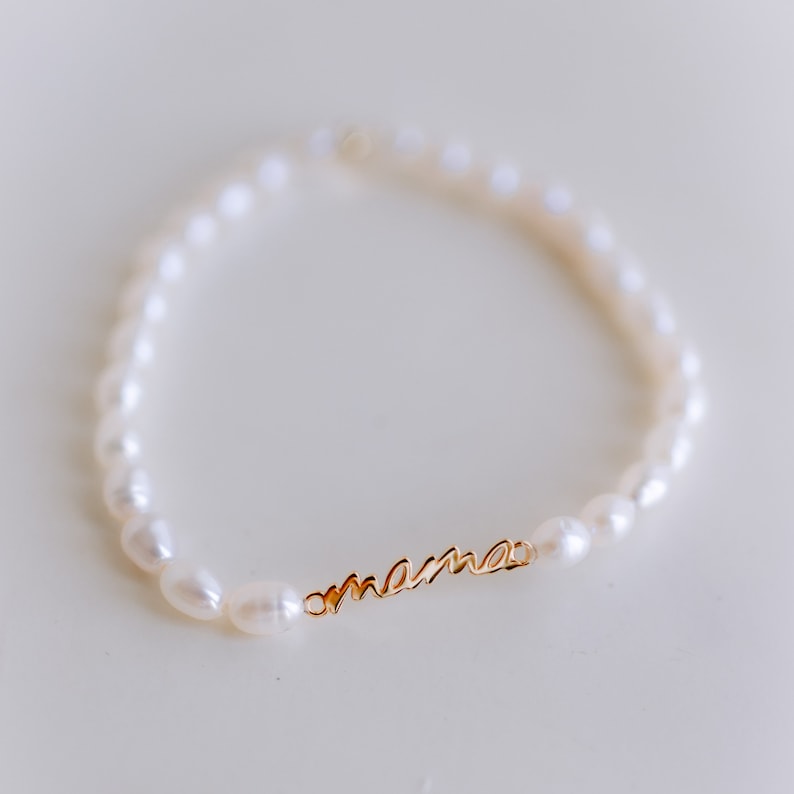 May include: A delicate pearl bracelet with a gold charm that reads "mama".