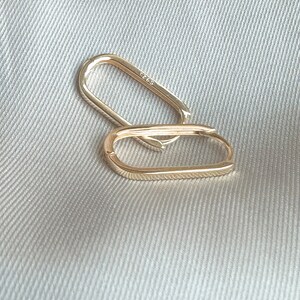 Pu&ograve; includere: Due orecchini a cerchio ovali in oro. Gli orecchini sono semplici ed eleganti e sarebbero un'ottima aggiunta a qualsiasi collezione di gioielli.