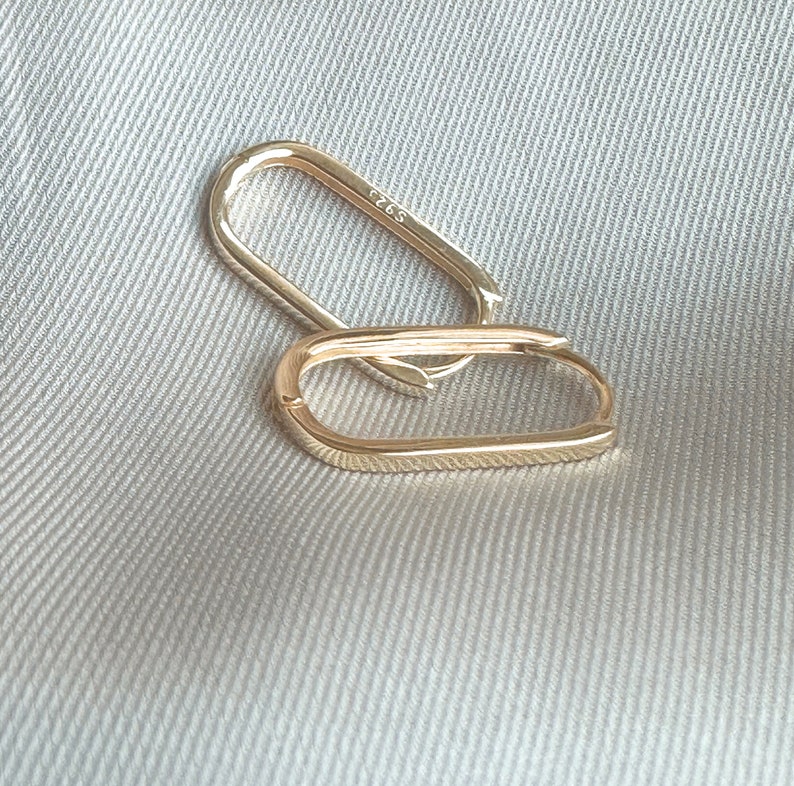Pu&ograve; includere: Due orecchini a cerchio ovali in oro. Gli orecchini sono semplici ed eleganti e sarebbero un'ottima aggiunta a qualsiasi collezione di gioielli.