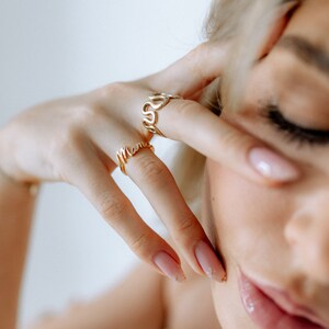 K&ouml;nnte beinhalten: Zwei goldene Ringe an einem Finger. Der obere Ring ist eine kursive Schrift, die "Love" buchstabiert, und der untere Ring ist eine kursive Schrift, die "Mama" buchstabiert.