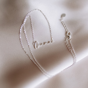 May include: A silver necklace with a delicate chain and a cursive 'amore' pendant.