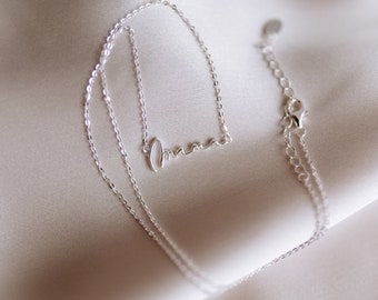 May include: A silver necklace with a delicate chain and a cursive 'amore' pendant.