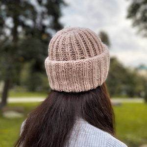 Puede incluir: Un gorro de punto rosa con textura de canal&eacute;. El gorro lo lleva puesto una persona con el pelo largo y casta&ntilde;o.