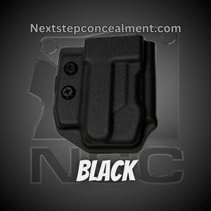 May include: Black holster with the text "BLACK" in white. The holster has a textured surface and is secured with two black screws. The website address "Nextstepconcealment.com" is visible at the top.