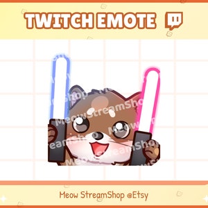 May include: A cartoon illustration of a brown and white dog holding two glowing lightsabers, one blue and one pink. The dog is smiling and has its tongue sticking out. The text "Twitch Emote 🪃" is at the top of the image.