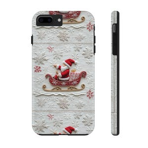May include: A white phone case featuring a 3D relief design of Santa Claus in a sleigh, surrounded by snowflakes. The case has a black border and a textured side. The Santa and sleigh are red and gold.